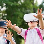 adorable little kids in virtual reality headsets playing together in park