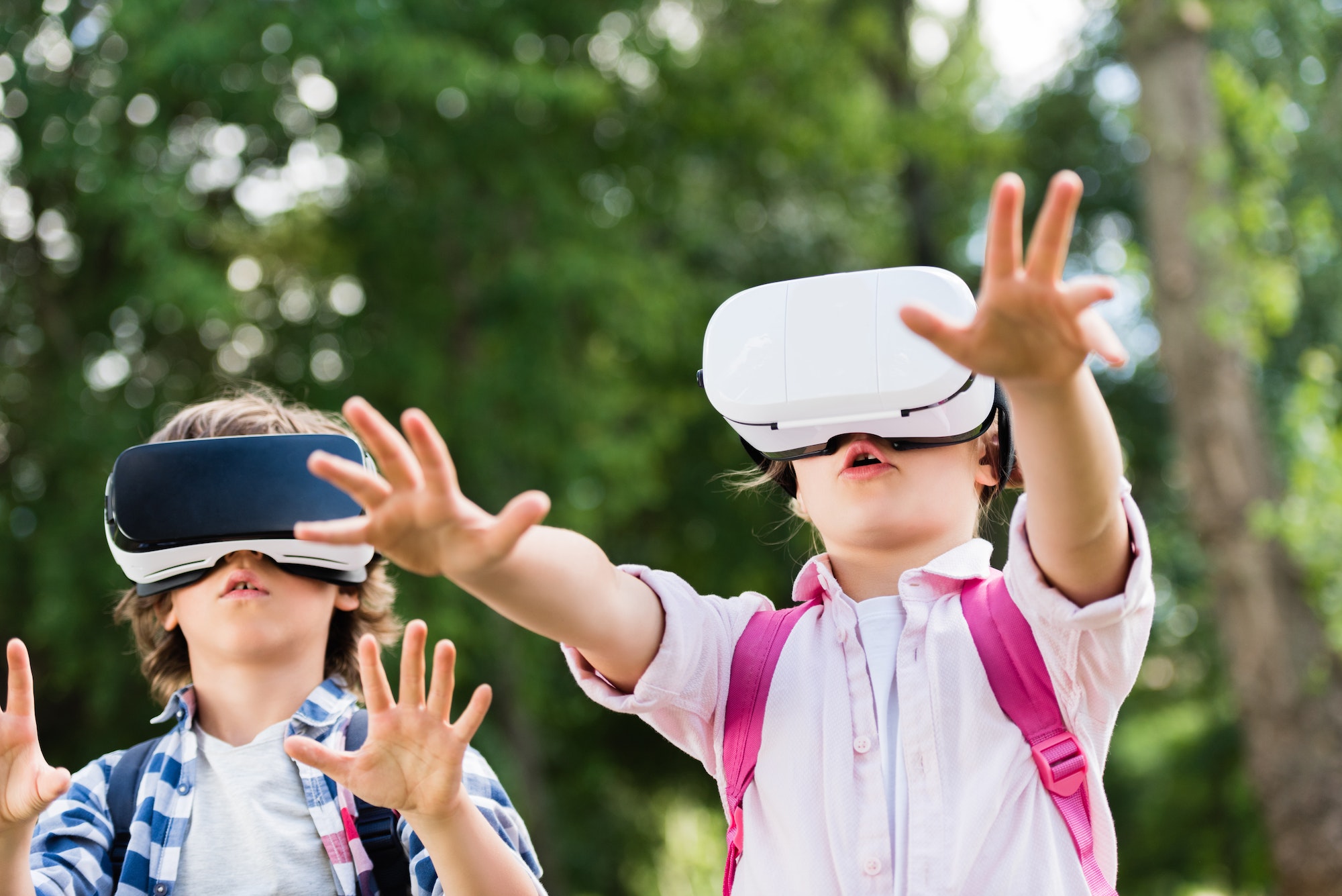 adorable little kids in virtual reality headsets playing together in park