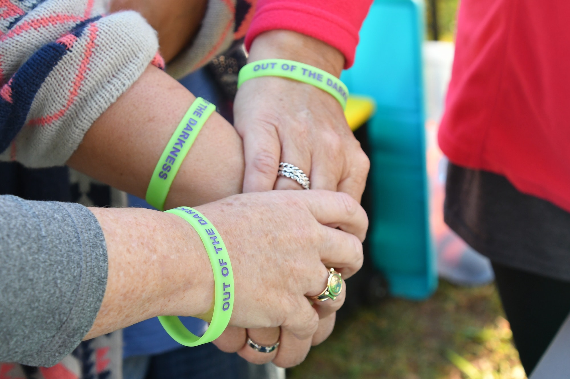 Showing support - hands with beads bracelets stacked in show of support at suicide prevention event