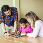 Teachers with girl painting on tablet computer in classroom