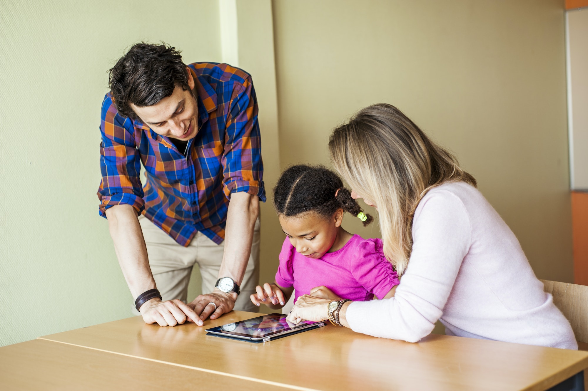 Teachers with girl painting on tablet computer in classroom